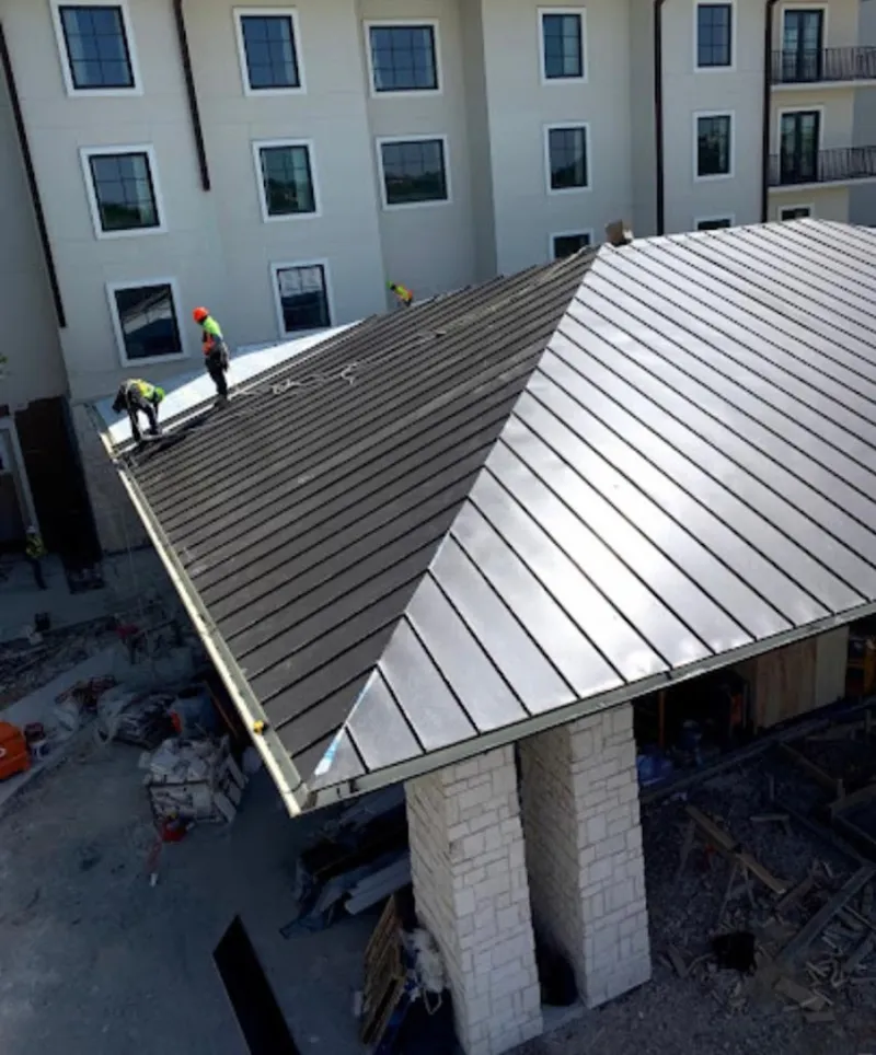 Crew installing standing seam metal roof panels on a commercial project in Hopewell